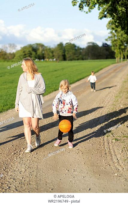 Family walking on dirt road by field
