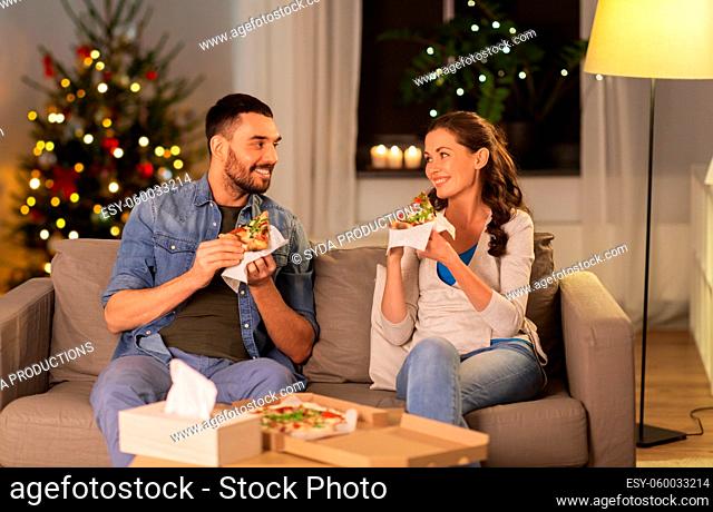 happy couple eating takeaway pizza on christmas