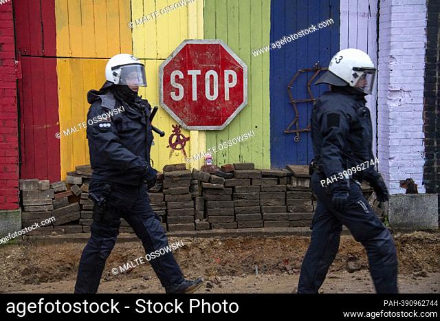 Two police officers walk in front of a stop sign, the police started to clear the town of Luetzerath on January 11, 2023