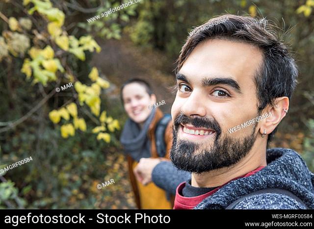 Smiling handsome man with girlfriend hiking in forest