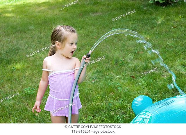 4-year old girl filling her inflatable pool with water  MR