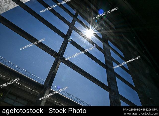 26 May 2023, Baden-Württemberg, Ravensbureg: The new building of Ravensburg Prison is completed. The sun shines through a barred window