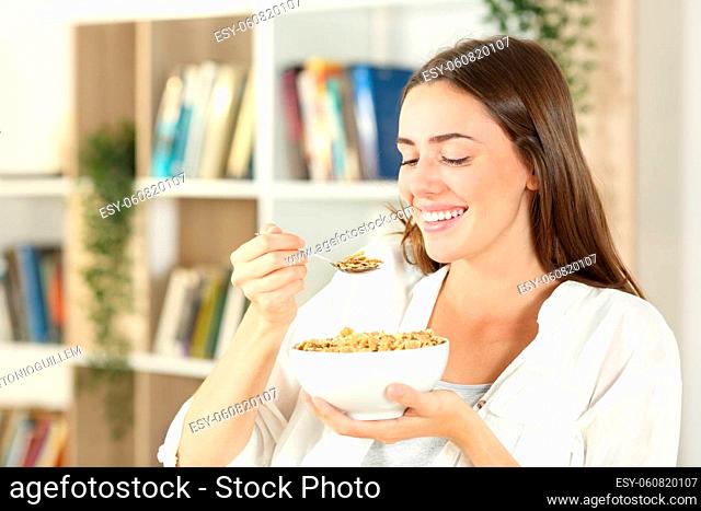 Happy woman eating cereals for breakfast sitting at home