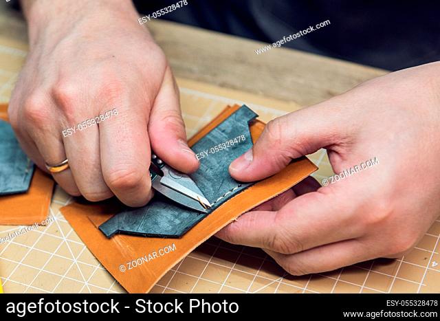 Man making leather wallet at a workshop. Concept of handmade craft production of leather goods