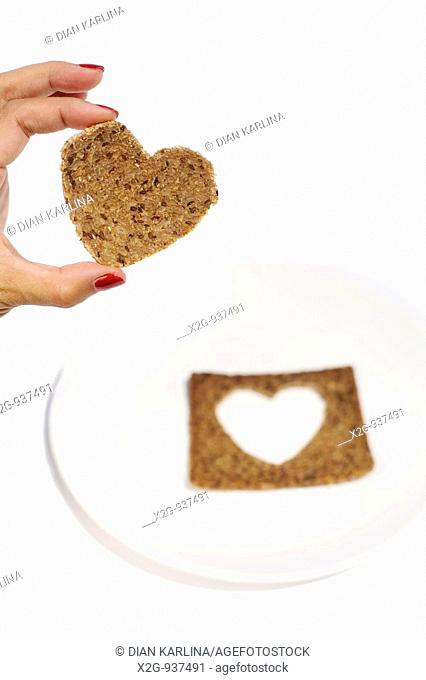 A woman's hand holding a heart-shaped rye bread