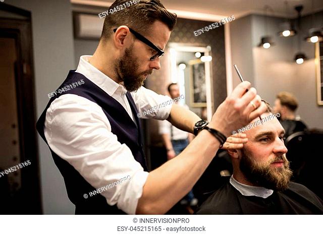 Profile portrait of barber focused on working on customer hair