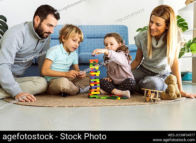 Parents looking at son and daughter playing jenga in living room