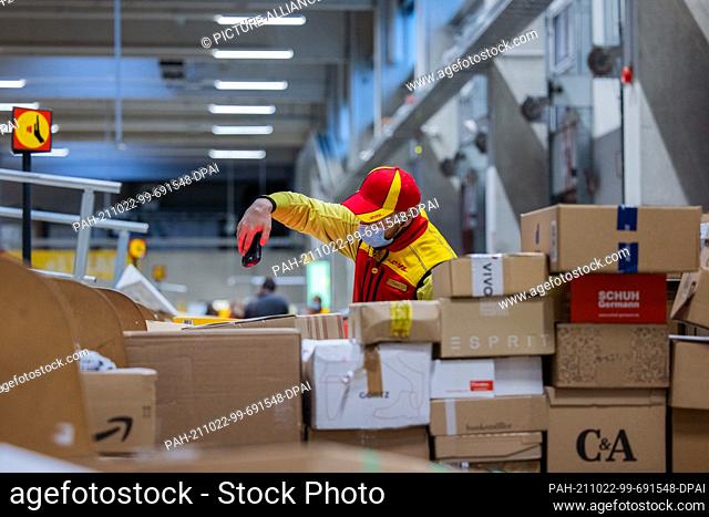 12 October 2021, North Rhine-Westphalia, Cologne: A parcel delivery driver sorts and puts parcels into a delivery vehicle at a Deutsche Post DHL delivery base