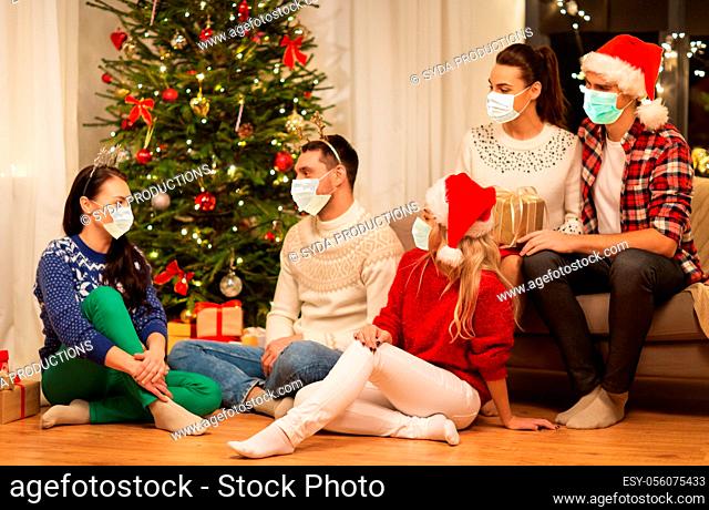 friends in masks celebrating christmas at home