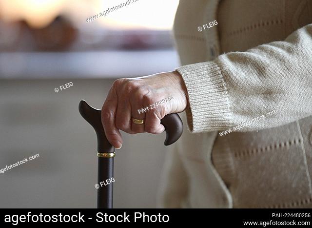 Topic picture - pensioner, senior citizen, older woman with rollator, walking aid and walking stick, stick and corona mask