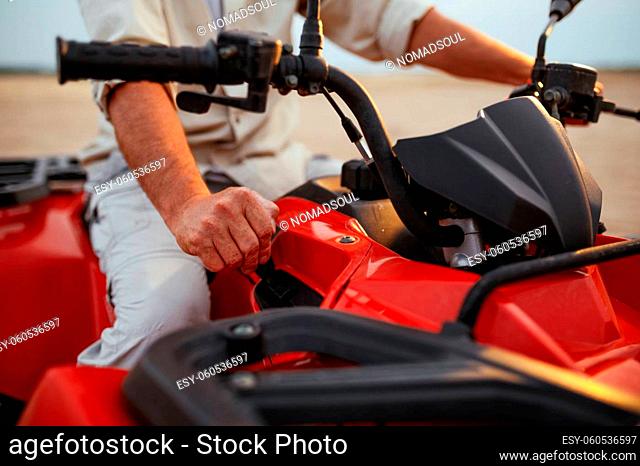 Atv racer in desert sands, closeup front view on hands. Male person on quad bike, sandy race, dune safari in hot sunny day, 4x4 extreme adventure, quad-biking