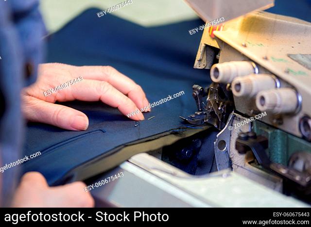 Seamstress sews clothes on a sewing machine. Textile factory