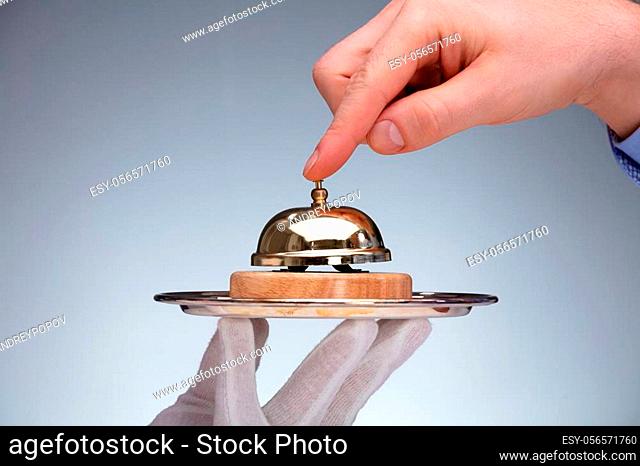 Close-up Of A Person's Hand Ringing Service Bell Hold By Butler