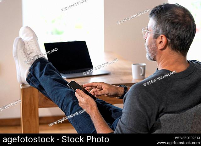 Businessman using mobile phone while sitting at home office