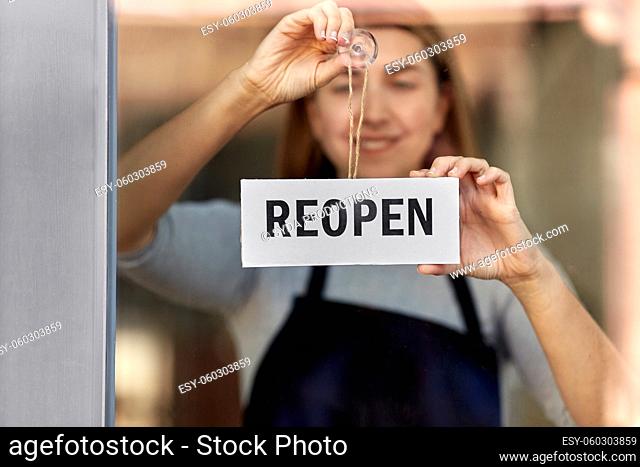 happy woman hanging reopen banner on door glass