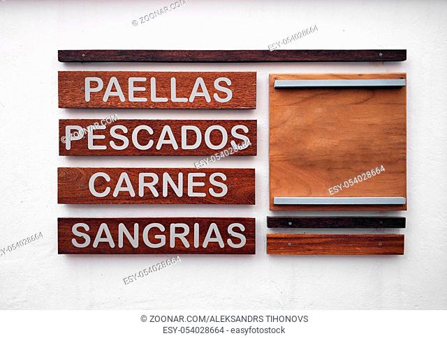 Restaurant menu in spanish on a white wall. Inscriptions of the food and beverage names. Paella, fish, meat and sangria