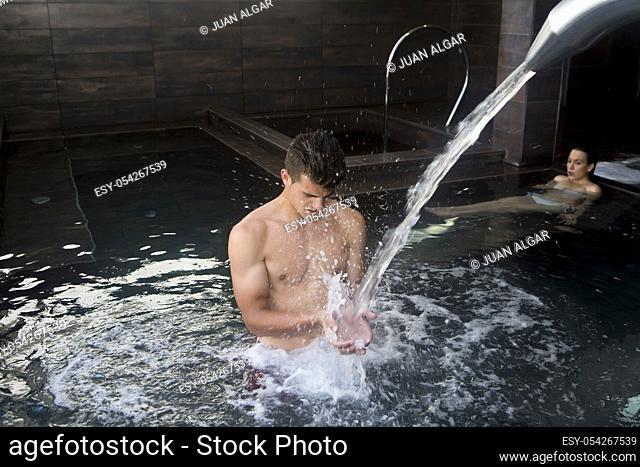Side view of wet-haired adult woman with eyes closed in bubbled water in spa