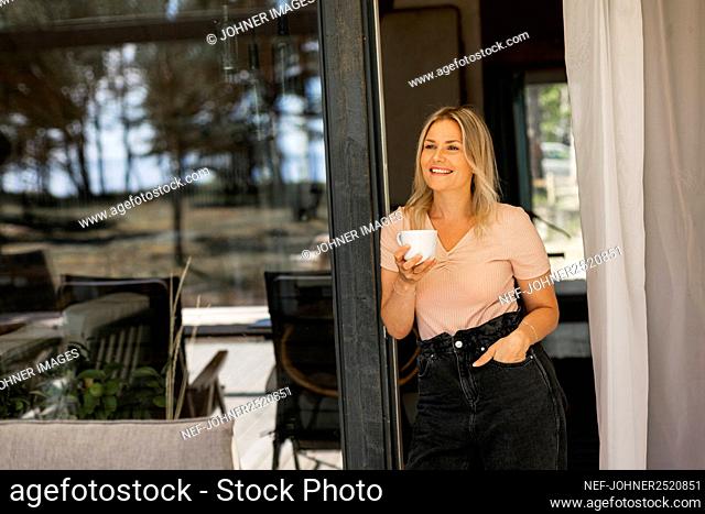 Smiling woman having coffee on patio