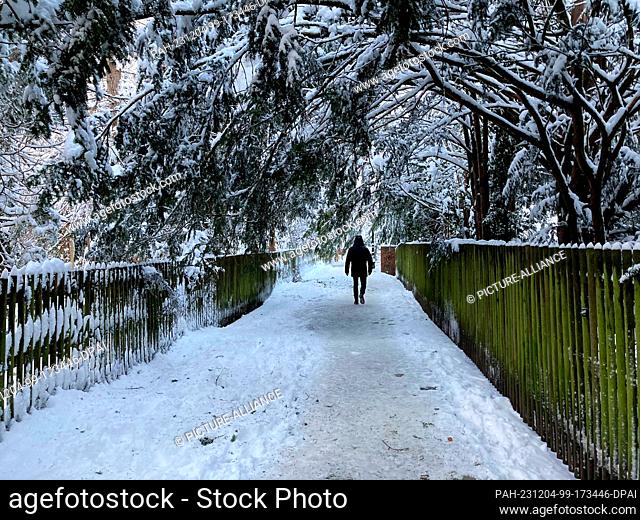 04 December 2023, Dachau: A person walks on a path covered in snow. Following the onset of winter, Munich Central Station is still only operating to a very...