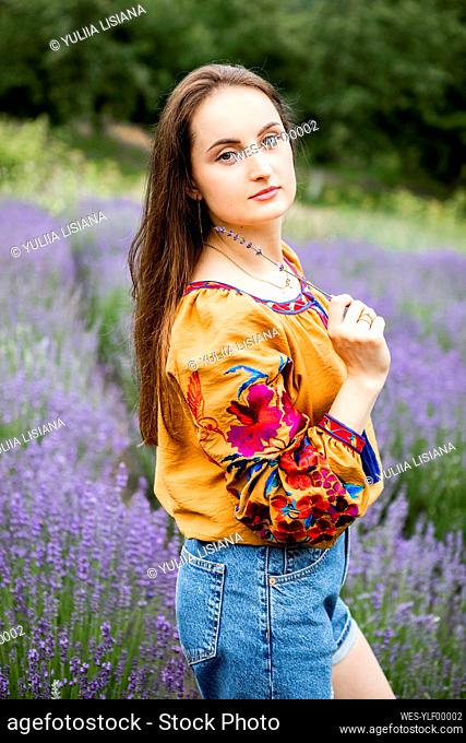 Beautiful woman with long hair standing at lavender field