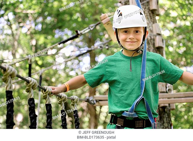 Caucasian boy balancing on rope bridge