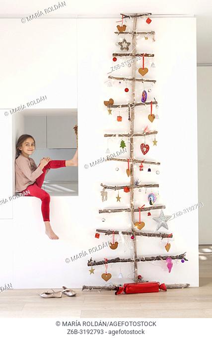 Little girl seated by a Christmas tree