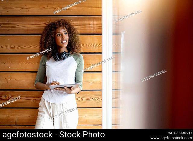 Smiling woman holding digital tablet while standing at home