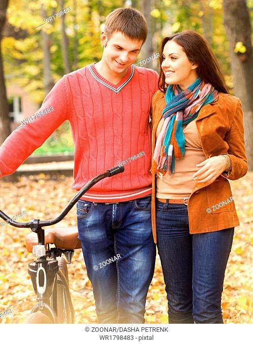 Happy young couple with bicycle in autumn park