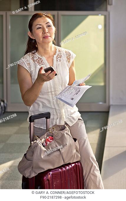 Mature woman checks air ticket at airport, Tokyo, Japan