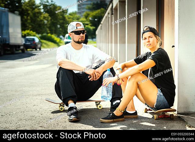 boy and girl with skateboards posing on the street on a summer day