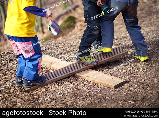 13 April 2022, Hessen, Büdingen: Children play on a simple seesaw they put together themselves at the ""Die Frischlinge"" forest kindergarten in a wooded area...
