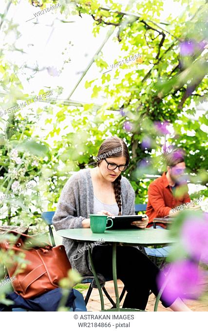 Woman working on tablet in coffee break at greenhouse