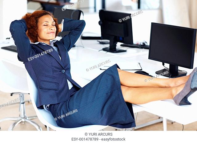 African American business woman relaxing in office with feet up on desk