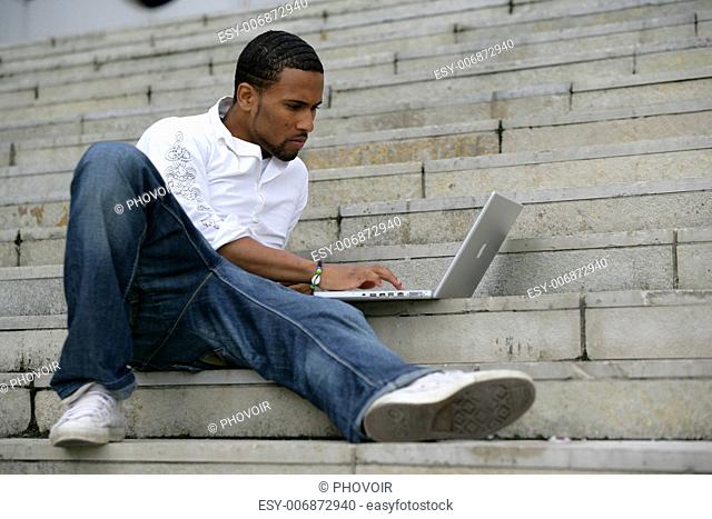 black man working on laptop in stairs