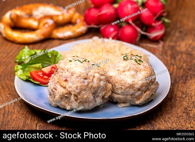 two speckknoedel with sauerkraut on wood