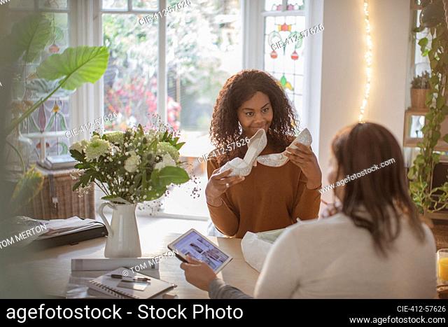Daughter showing wedding shoes to mother at dining table