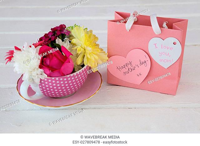 Close-up of paper bag with message and fresh flowers