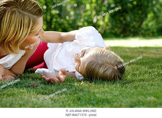 Mother and daughter lying on the lawn talking, Sweden