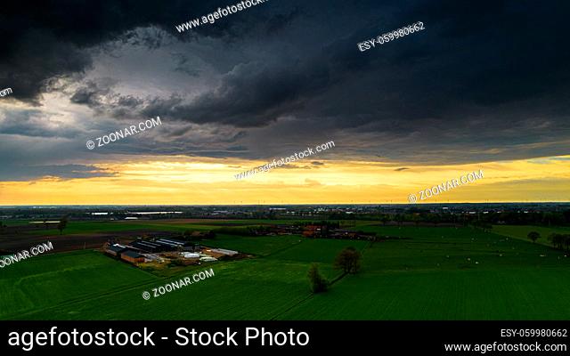 Aerial landscape of countryside with colorful storm clouds. Extreme thunderstorm over a farm and agricultural fields and road. High quality photo