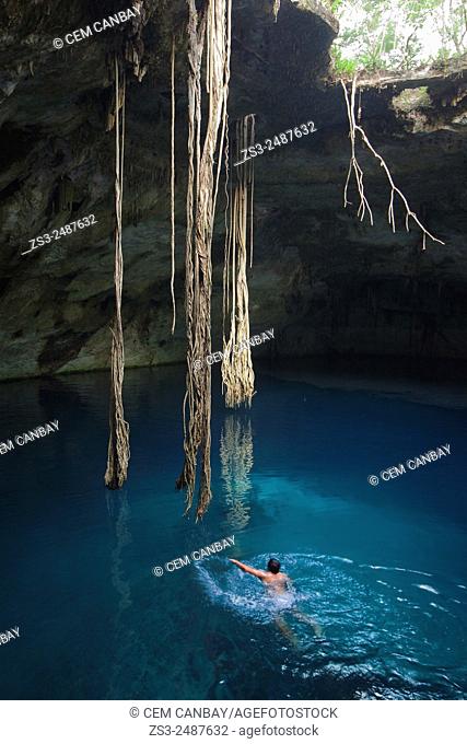Young mexican man swimming in Cenote Nayah, Tecoh, Yucatán, Mexico, Central America