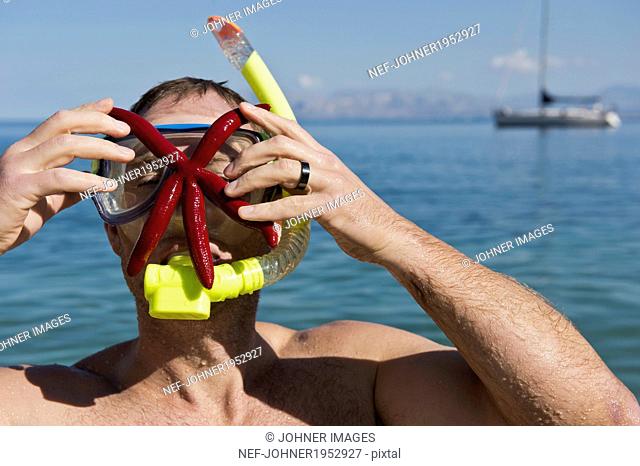 Man with starfish on his face, Sicily, Italy