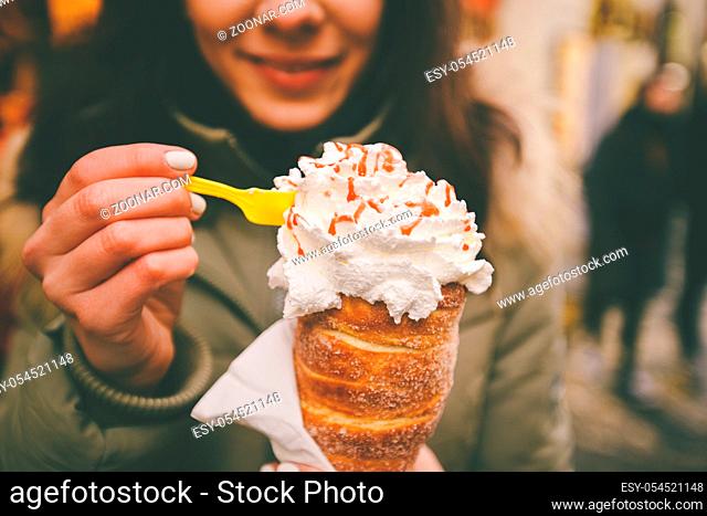 trdelnik or Trdlo with cream in the hands of a beautiful winter girl in the Czech Republic, Prague at the Christmas market