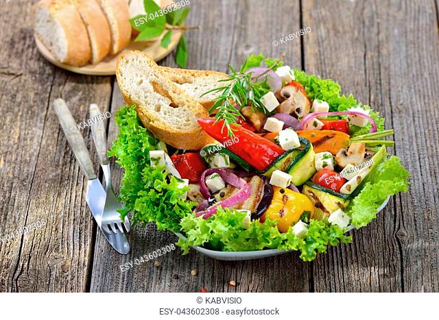 Mixed grilled Greek style vegetables with feta cheese on green salad served with toasted bread
