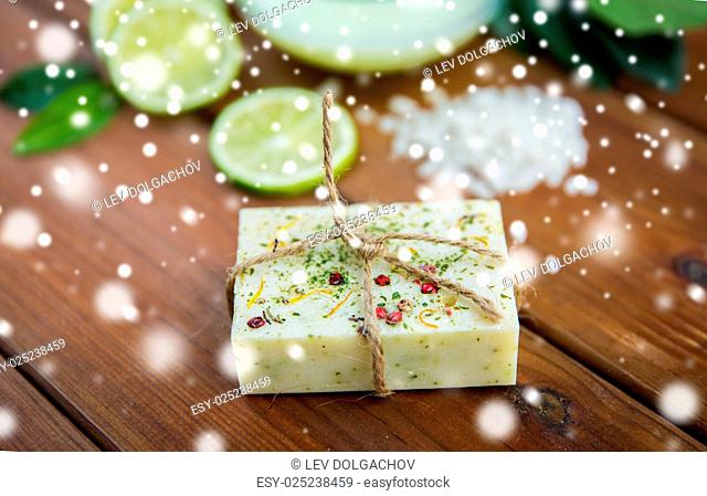 beauty, spa, bodycare, bath and natural cosmetics concept - handmade herbal soap bar on wood over snow