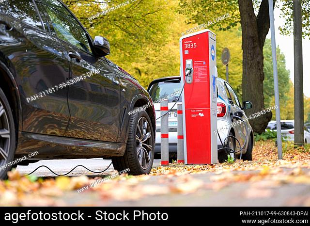 17 October 2021, Hamburg: An SUV and a small car stand with connected charging cables at a public charging station. By 2030