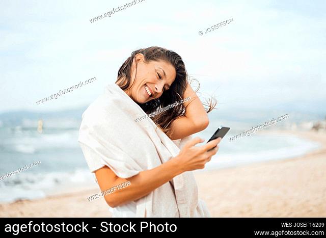 Happy woman using smart phone at beach