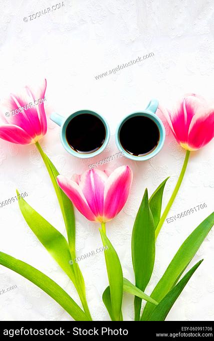 two cups of coffee and three beautiful pink tulips