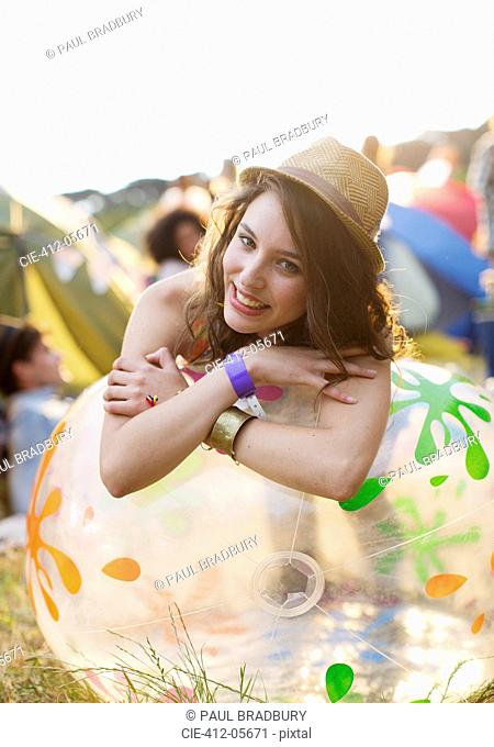 Portrait of happy woman leaning on inflatable chair outside tents at music festival