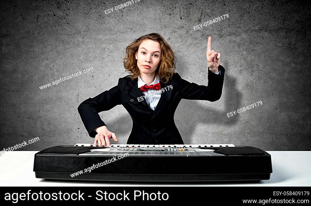 Funny crazy woman in suit and bow tie playing piano and pointing with finger up