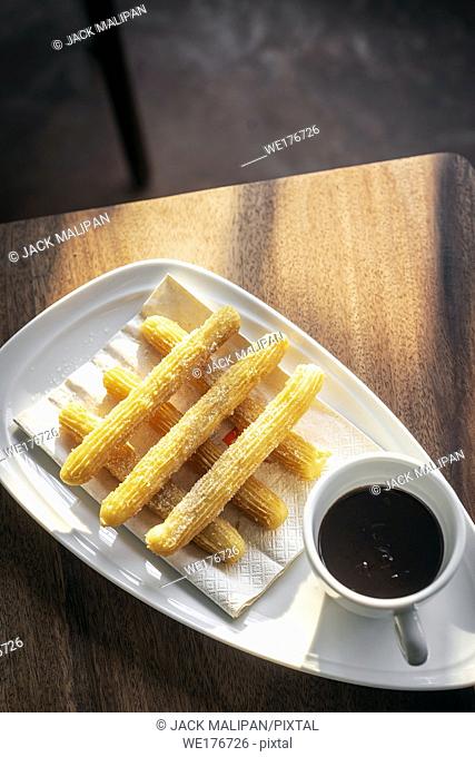 churros con chocolate traditional spanish sweet breakfast set on wooden table